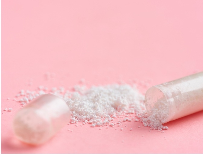 膠囊裡頭的藥粉末散在粉色桌面上