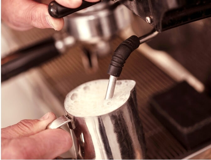 男子利用咖啡機蒸氣噴頭將牛奶製作成奶泡