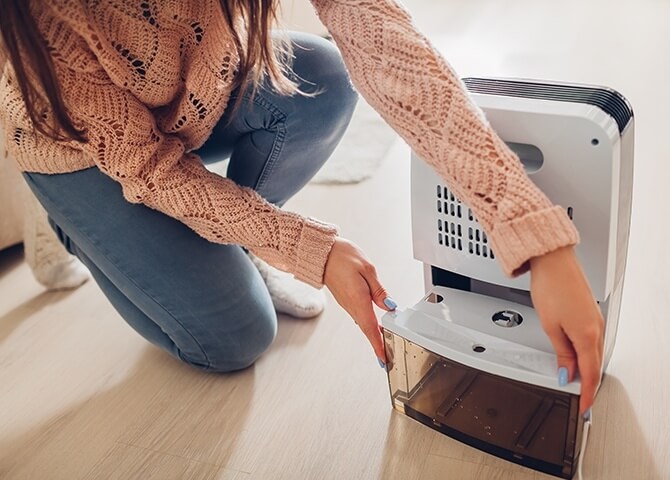 女子正在將水箱放回除濕機中