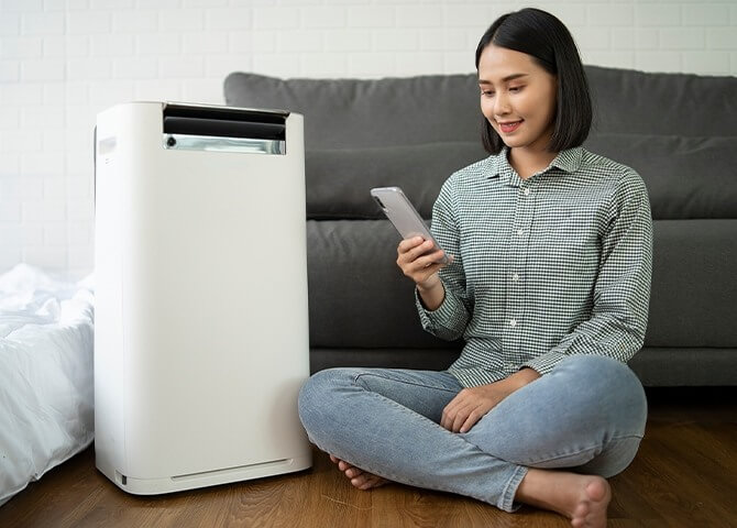 女子使用遙控器調整設定除濕機