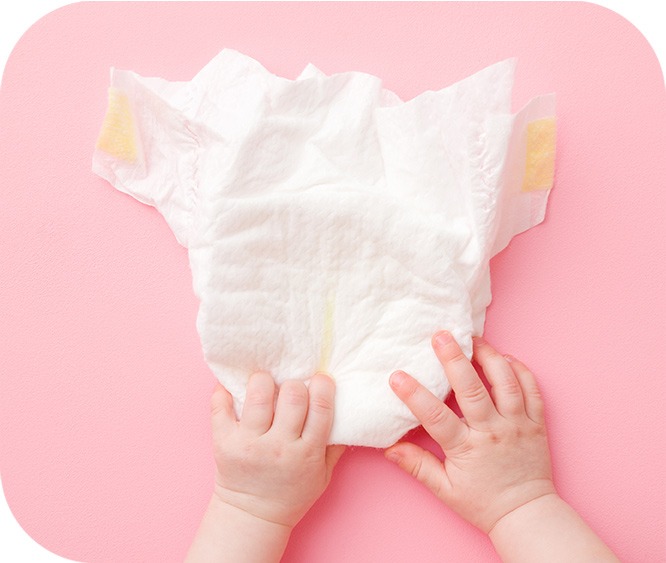 特寫嬰兒的手撫摸著白色的尿布在粉紅色的桌面上