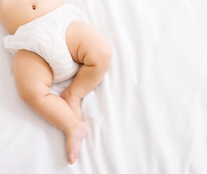 穿著尿布的寶寶躺在乾淨舒適的白色床鋪上