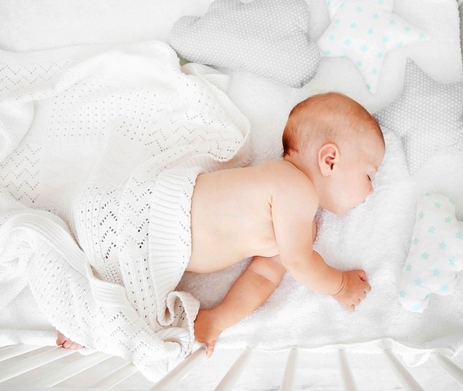 寶寶躺在白色枕頭、棉被中熟睡