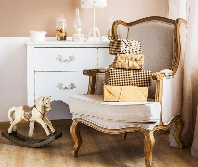 米白色歐式古典單人沙發上擺著各式包裝的禮物，旁邊還有一個木製搖搖馬