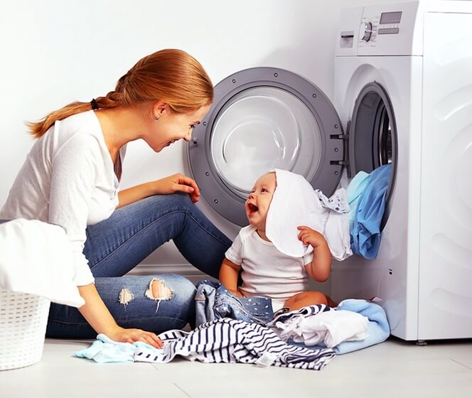 媽媽和寶寶正在收滾筒式洗衣機裡的衣服