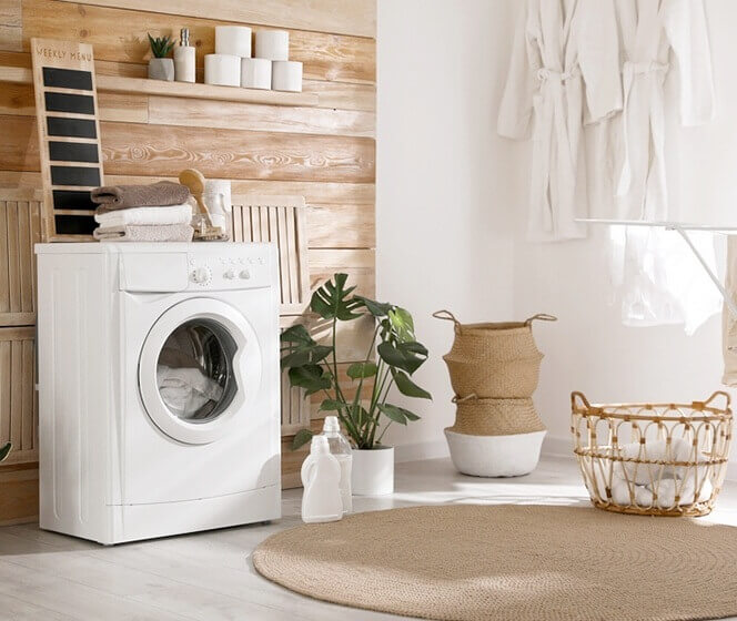 白色滾筒洗衣機、洗衣籐籃、麻料地墊、綠色植栽，營造出簡約舒適的居家風格